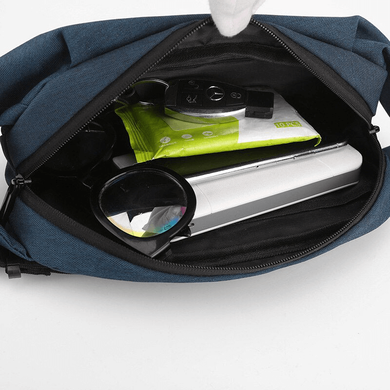 Open waterproof crossbody bag revealing organized interior with various items including a magnifying glass, keys, and a book.